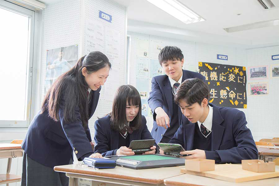 教室でゲーム機を囲んで学ぶ生徒たち